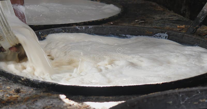 the worker pouring creamy white soy milk into the hot wok.