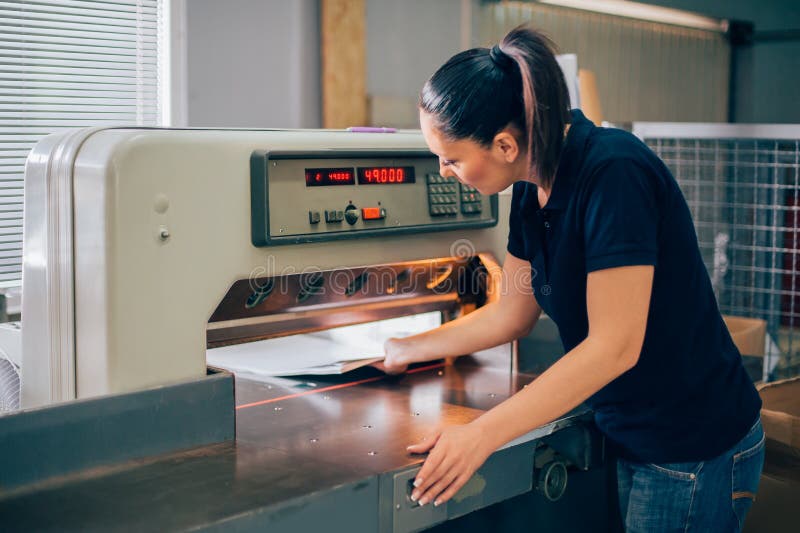 Worker in printing centar uses paper guillotine machine knife royalty free stock image