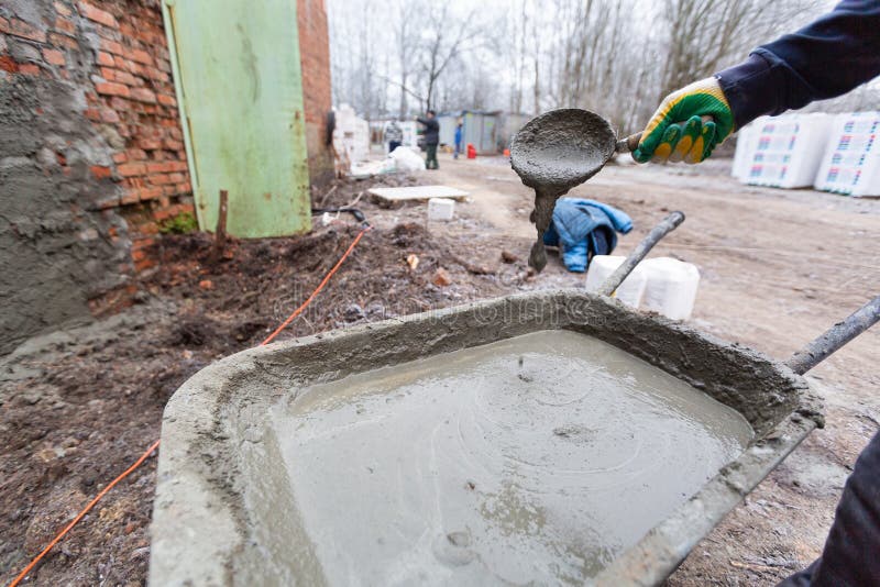 Worker in Protect Gloves is Mixing Up the Liquid Cement in Construction