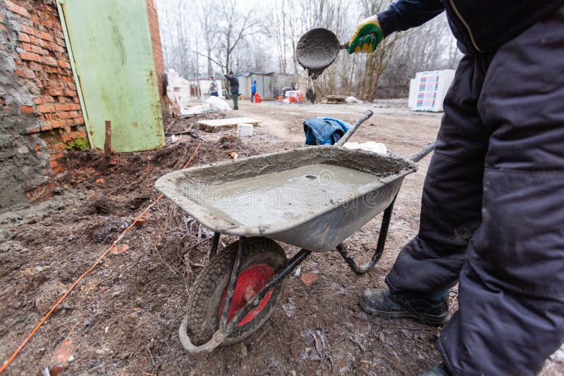 Worker in Protect Gloves is Mixing Up the Liquid Cement in Construction