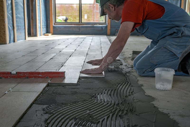 The Worker Puts Ceramic Tiles on the Construction Site Stock Photo