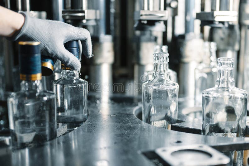 Worker puts plastic cap on bottle of luxury vodka in shop