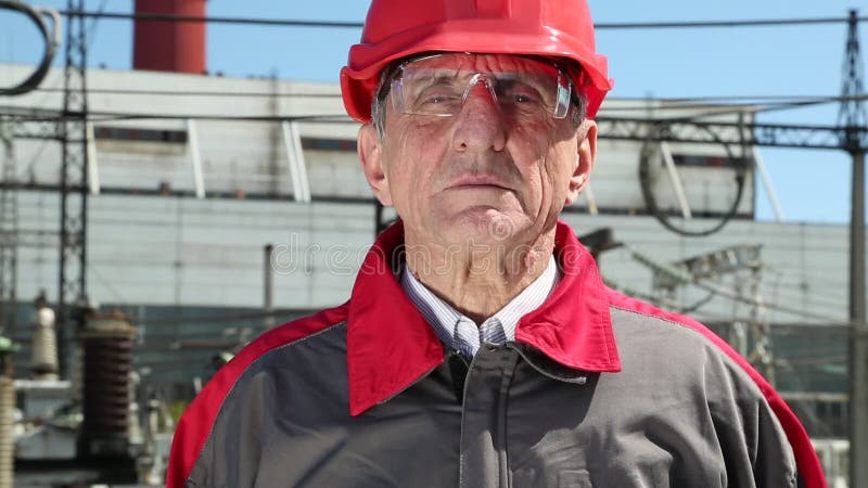 Worker in red hard hat at nuclear power plant looking at the camera