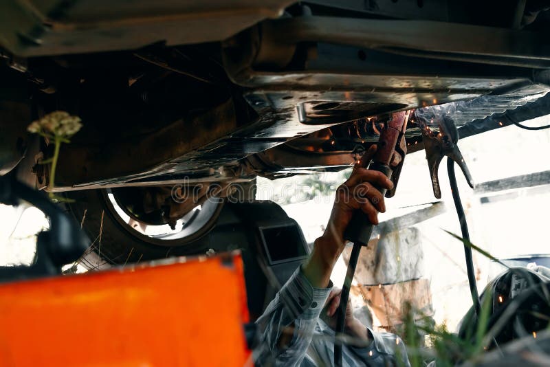 Worker repairing car body,Repair service worker fix damaged car after crash on the road. Working with welding tool to fix metal