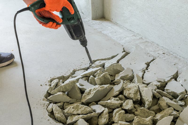 Worker Smashes Concrete Floor with Electric Hammer Drill Stock Photo