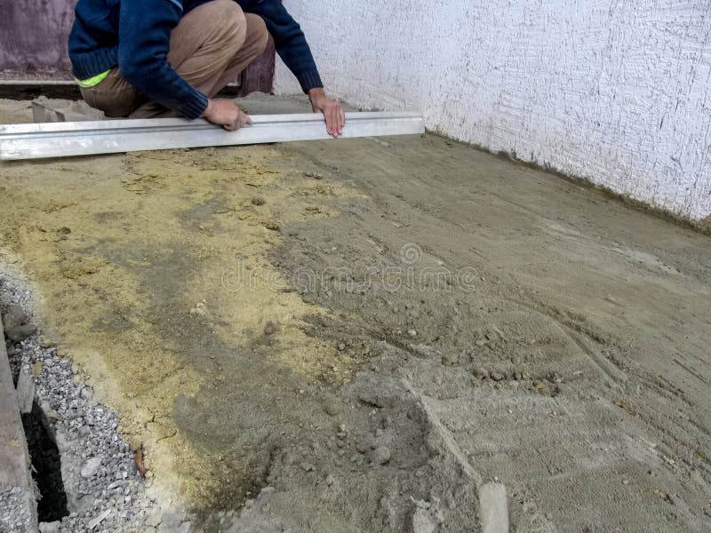 Worker smoothing dry sand-cement mixture on the surface of a building site outdoors. Preparatory stage for paving slab laying. Works. Background with copy space royalty free stock photography Worker smoothing dry sand-cement mixture on the surface of a building site outdoors. Preparatory stage for paving slab laying. Works. Background with copy space royalty free stock photography