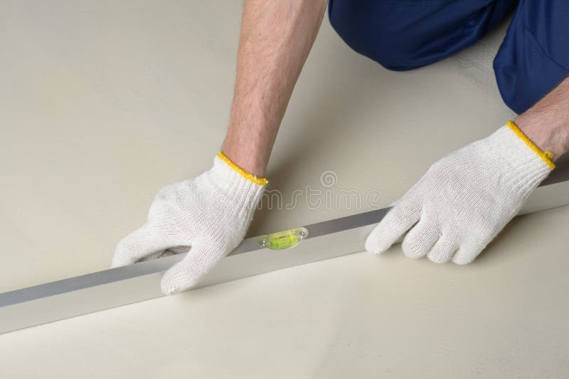 Construction worker measures the quality of floor using spirit level. Construction worker measures the quality of floor using spirit level