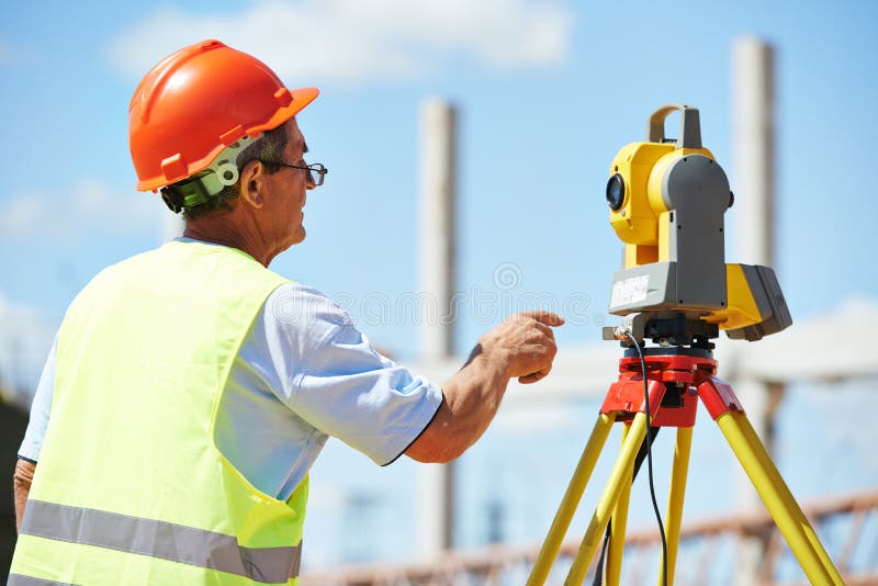 Builder worker with theodolite transit equipment at construction site outdoors during surveyor work
