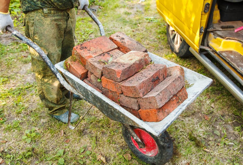 Worker is transporting a brick in a wheelbarrow