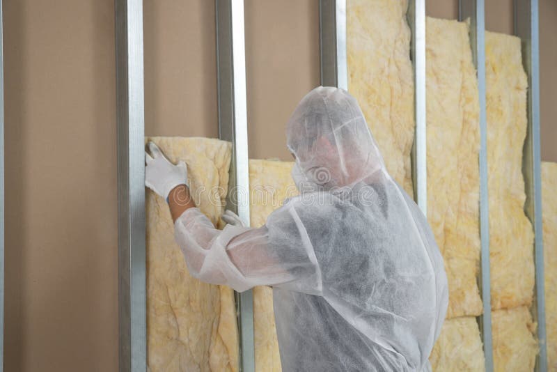 Worker in uniform insulating wall indoors, back view royalty free stock image