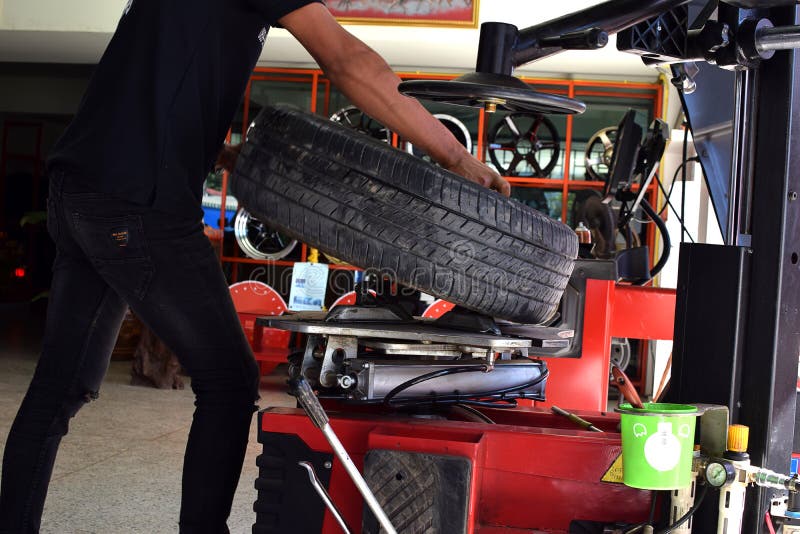 Worker use tire changer matchine in tire car shop.