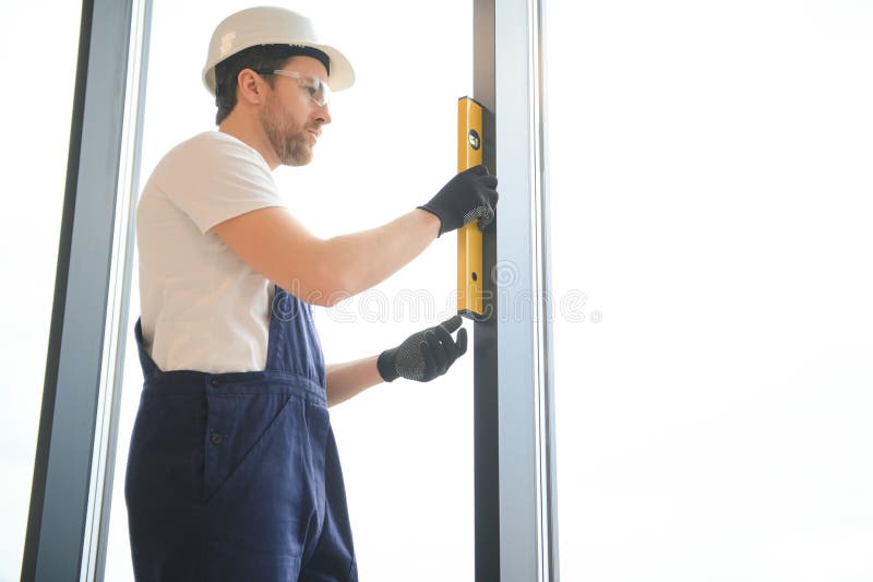 Worker Using Bubble Level after Plastic Window Installation Indoors