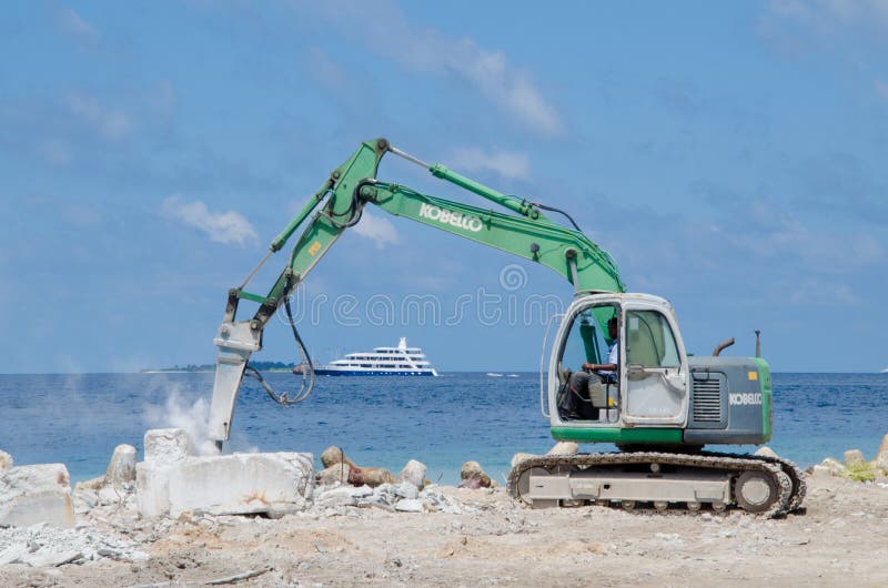 Worker using excavator at construction site on shore of ocean stock photos Worker using excavator at construction site on shore of ocean stock photos