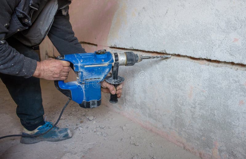 Worker Using a Jackhammer To Drill into Wall for Electricity
