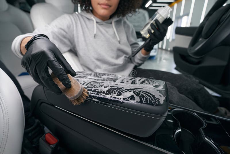 Worker using leather cleaner and brush for cleaning car upholstery