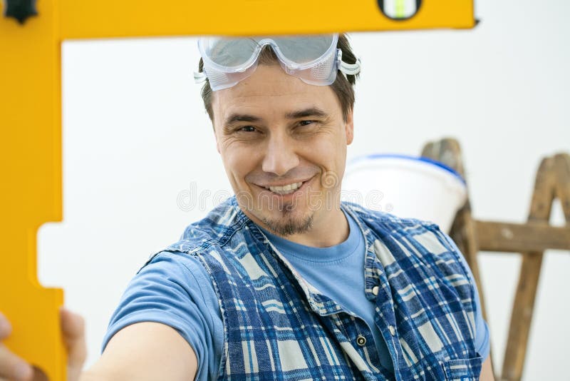 Worker measuring with square level tool, smiling. Isolated on white background. Worker measuring with square level tool, smiling. Isolated on white background.