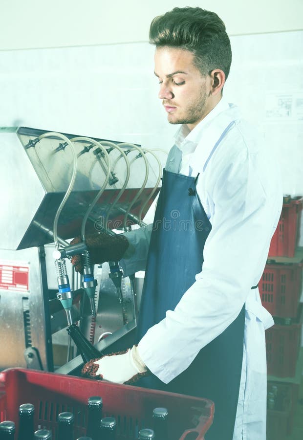 Worker Using Machine To Bottle Wine at Sparkling Wine Factory Stock
