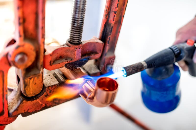 worker using propane gas torch for soldering copper pipes.