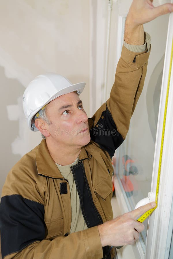 Worker using tape measure window in construction site royalty free stock image Worker using tape measure window in construction site royalty free stock image