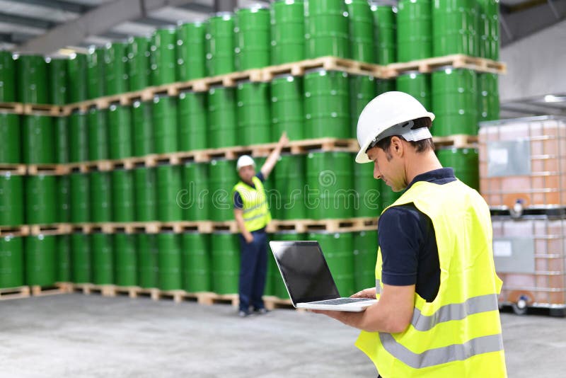 Worker in a warehouse with oil barrels checks the stock stock images Worker in a warehouse with oil barrels checks the stock stock images