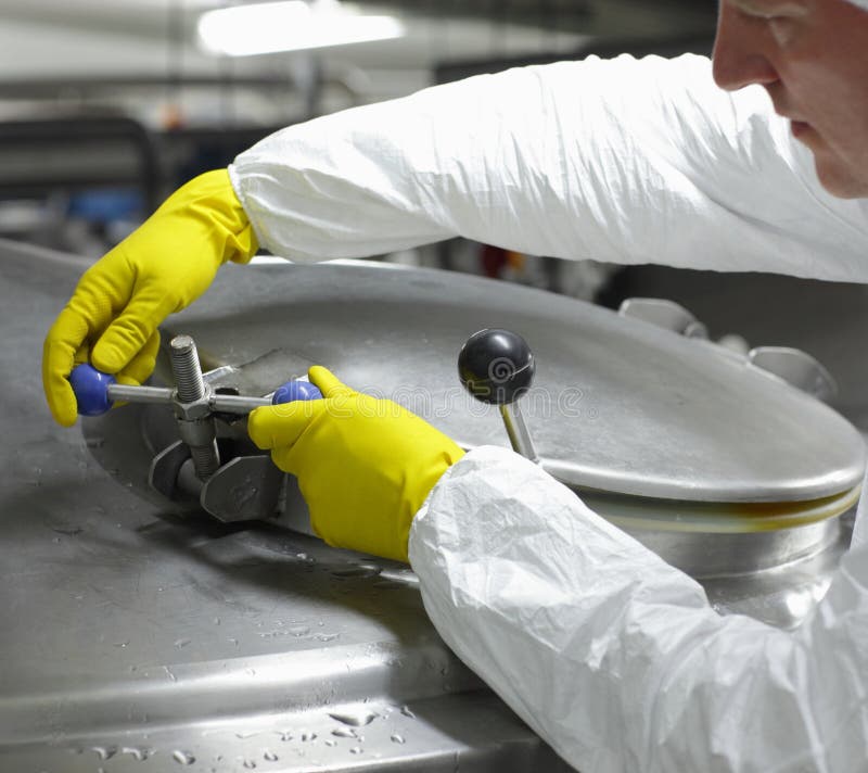 Worker in yellow gloves closing industrial process tank