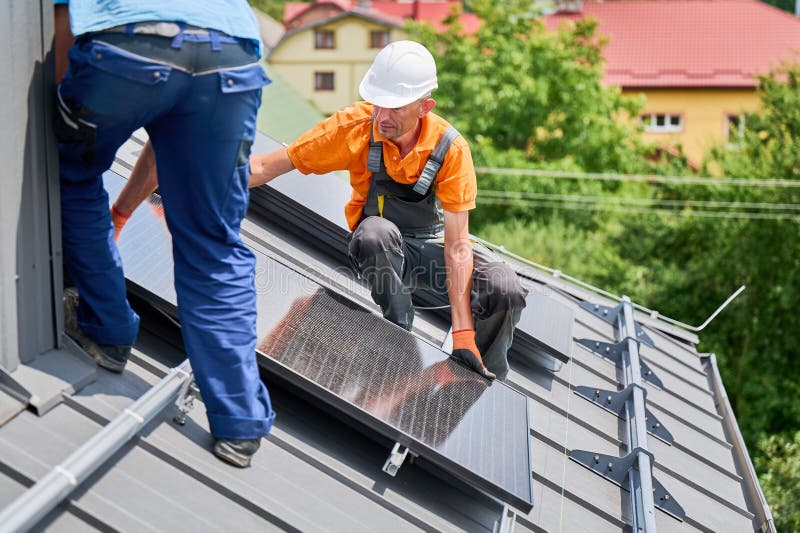 Workers building solar panel system on roof of house. Men installing photovoltaic solar module stock image