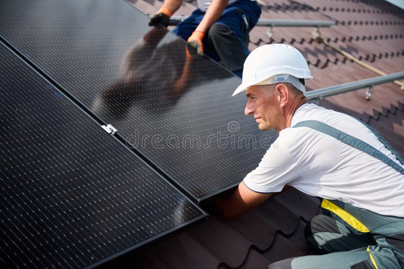 Workers building solar panel system on roof of house. Men installing photovoltaic solar module royalty free stock photography