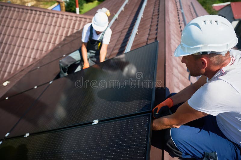 Workers building solar panel system on roof of house. Men installing photovoltaic solar module royalty free stock photography