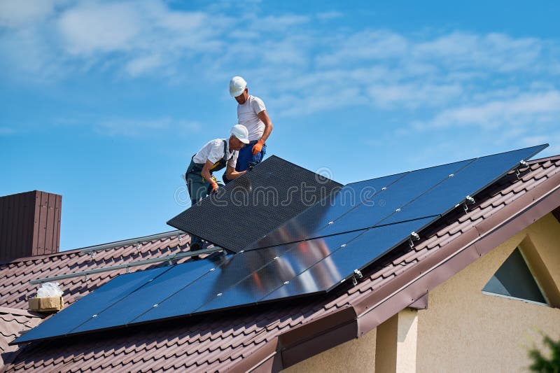 Workers building solar panel system on roof of house. Men installing photovoltaic solar module royalty free stock images