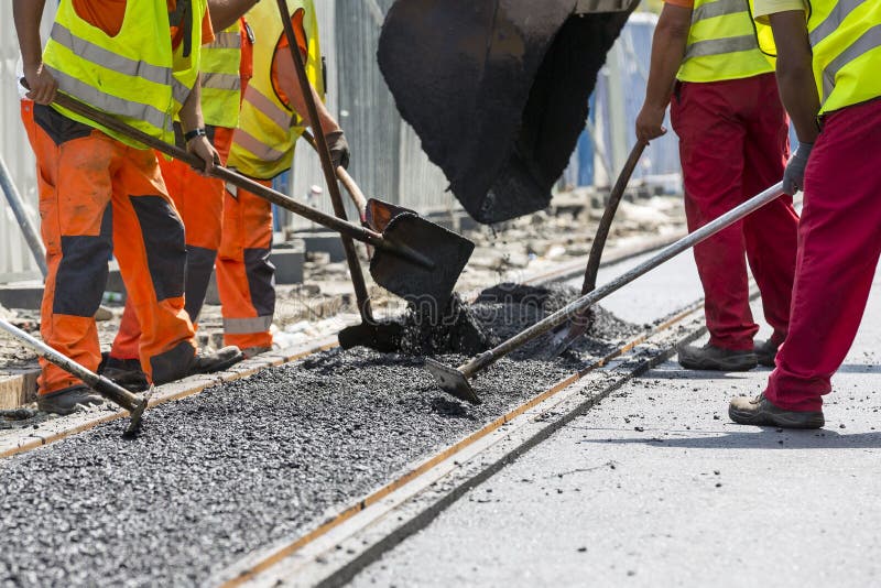 Workers construct asphalt road and railroad lines