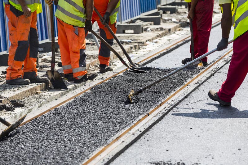 Workers construct asphalt road and railroad lines