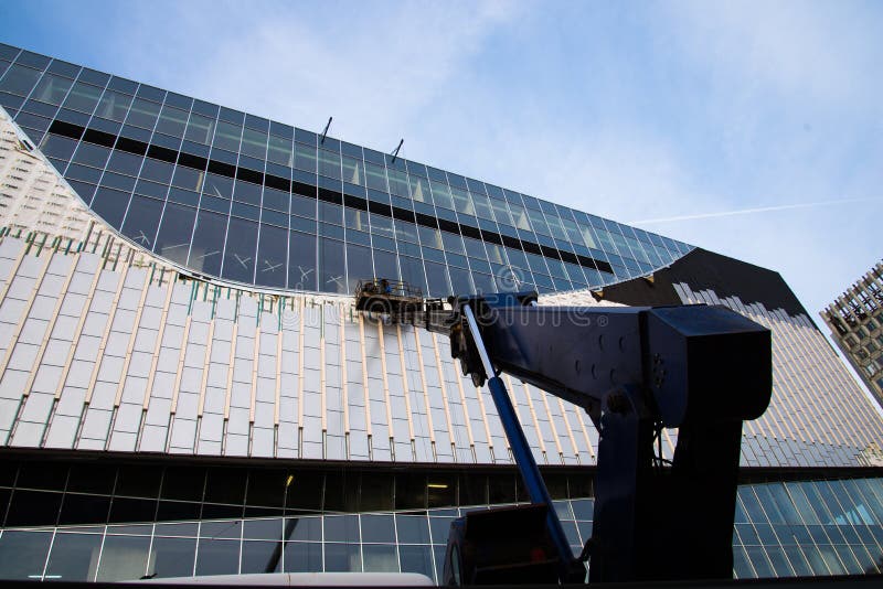 Workers at height establish ventilated facades. The work takes place in a cradle on a telescopic boom stock images