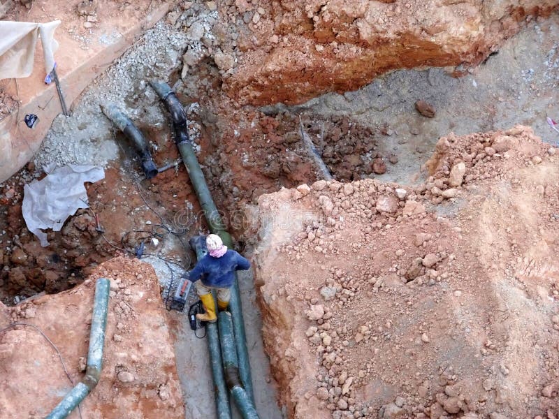 Workers Installing Underground Utility and Services Pipe in the Shallow