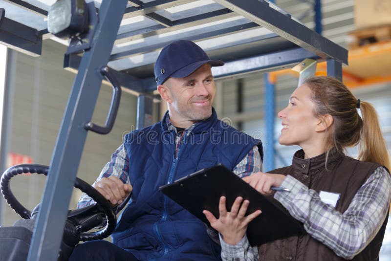 workers-in-logistics-warehouse-at-forklift-checking-list-stock-image