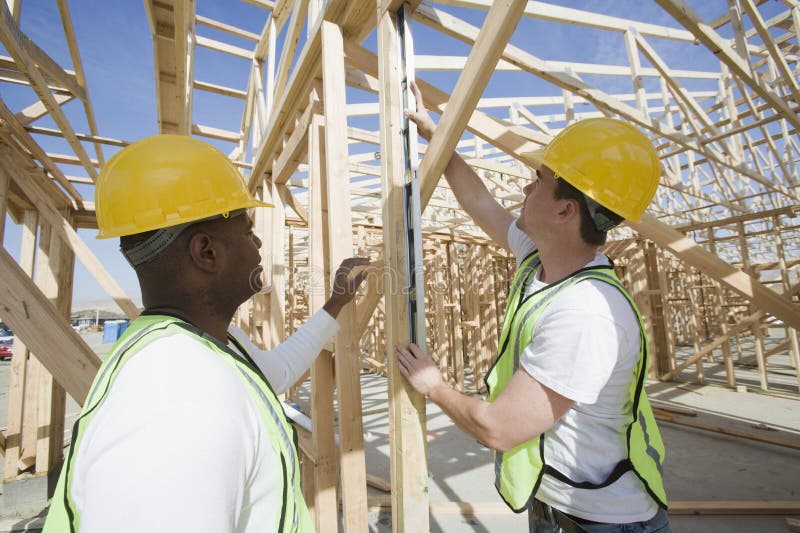 Workers measuring wooden beam at construction site. Workers measuring wooden beam at construction site