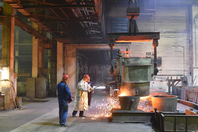 Workers in protective equipment in a foundry during the production of steel components - workplace industrial factory