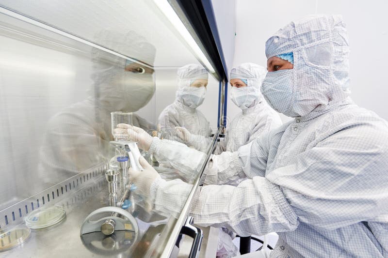 Female science researchers in protective uniform and equipment works with dangerous hazard virus material at microbilogy laboratory. Female science researchers in protective uniform and equipment works with dangerous hazard virus material at microbilogy laboratory