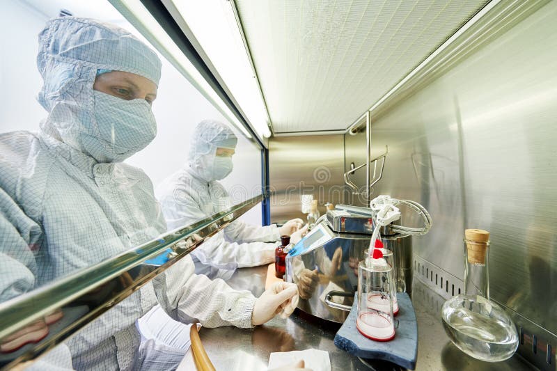 Female science researchers in protective uniform and equipment works with dangerous hazard virus material at microbilogy laboratory. Female science researchers in protective uniform and equipment works with dangerous hazard virus material at microbilogy laboratory