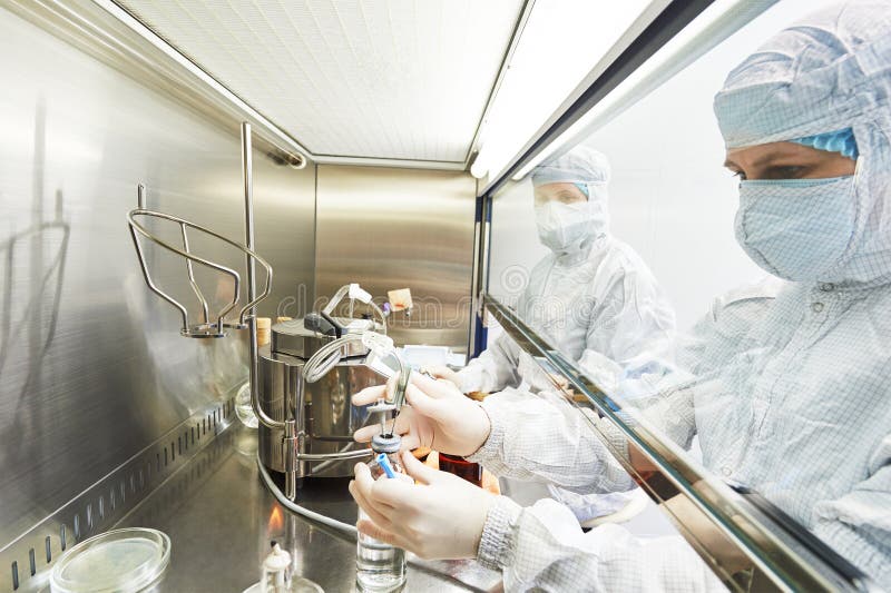 Female science researchers in protective uniform and equipment works with dangerous hazard virus material at microbilogy laboratory. Female science researchers in protective uniform and equipment works with dangerous hazard virus material at microbilogy laboratory