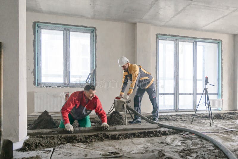 Workers in Work Clothes are Doing Their Job, Leveling the Floor and Pouring Concrete Stock Image