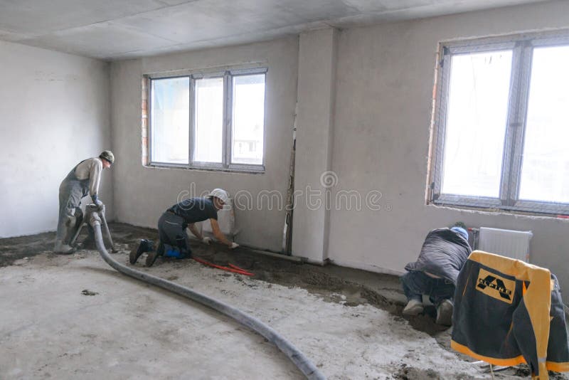 Workers in Work Clothes are Doing Their Job, Leveling the Floor and