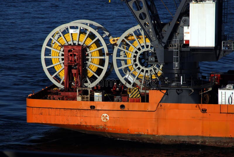 Worker look on as a large ship spools out umbilical control cable as part of a deepwater well completion. Worker look on as a large ship spools out umbilical control cable as part of a deepwater well completion.