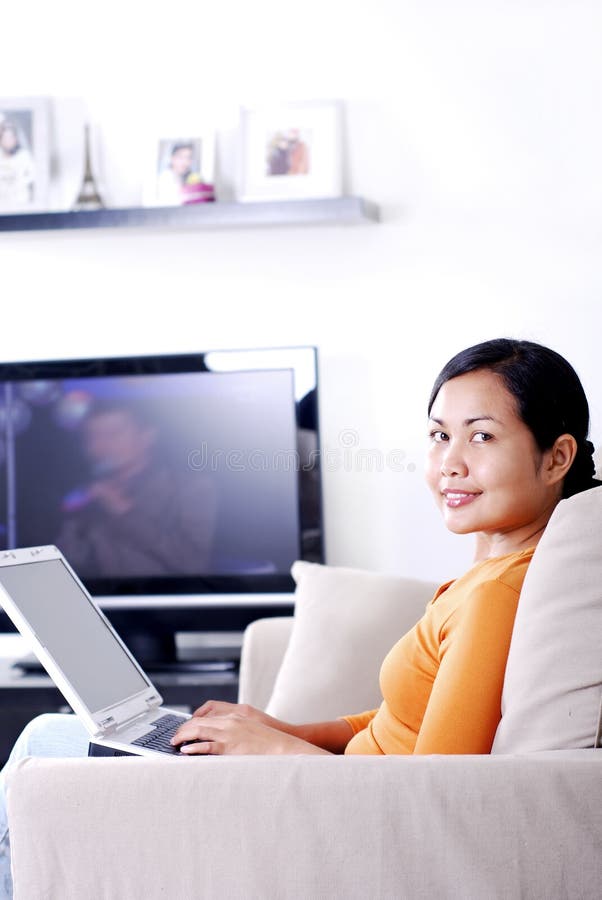 Mujer sobre el sofá computadora portátil en sala de estar.