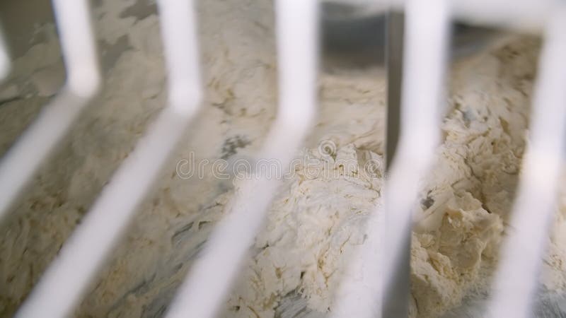 Working mixer through white grille while mixing dough