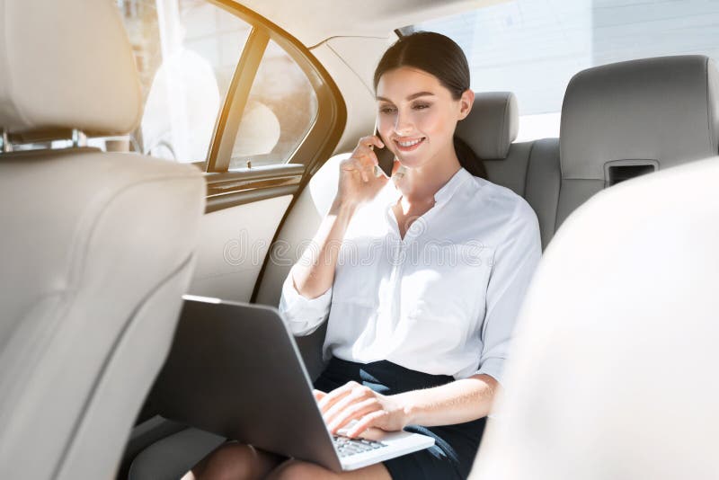 Female lawyer working on laptop, sitting in car