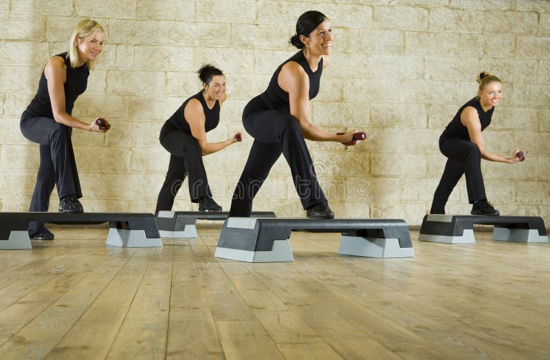 A group of women exercising with dumbbells in the fitness club. Low angle view. A group of women exercising with dumbbells in the fitness club. Low angle view.