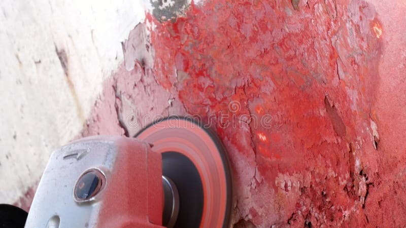 Working people tear off paint on metal in repairs process at shipyard.