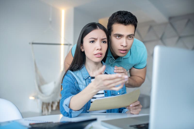 Brunette male and dark-haired female checking something on laptop, looking concerned