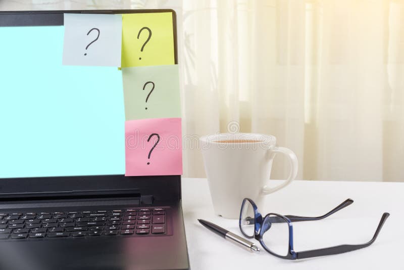 The working table of the freelancer. Stickers with question marks stick to the laptop. stock photo