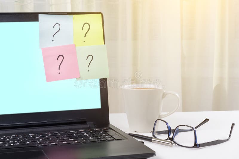 The working table of the freelancer. Stickers with question marks stick to the laptop. stock photography